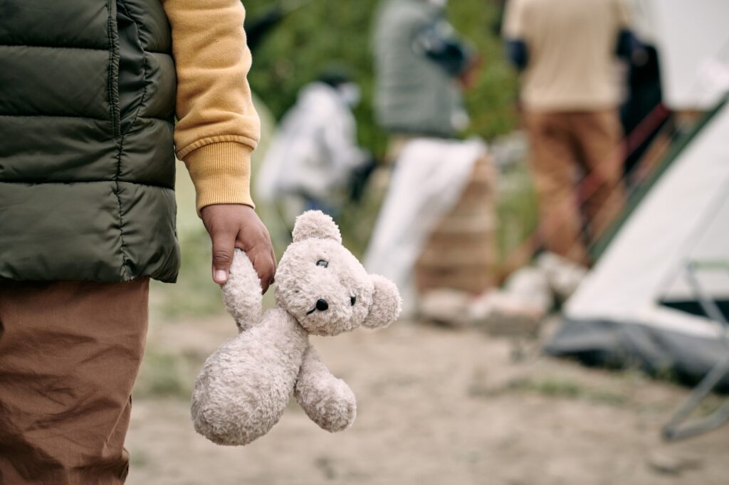 Hand of homeless child holding white teddybear